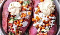 two baked potatoes with chickpeas and yogurt in a metal bowl on a table