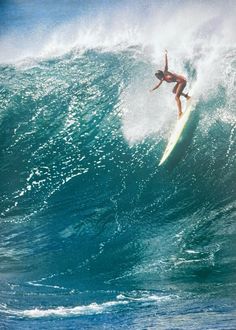 a person on a surfboard riding a wave in the ocean with their arms up