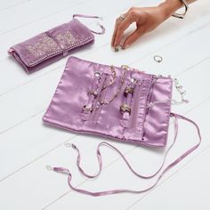 a woman's hand is holding an open purple purse on the floor next to other items