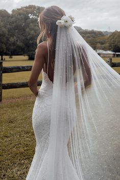 the back of a bride's wedding dress, with her veil blowing in the wind