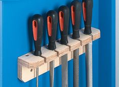 four black and red tools are on the side of a blue wall with five holes in it