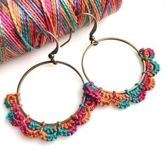 the hoop earrings are decorated with multicolored crocheted beads and metal hooks