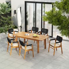 an outdoor dining table and chairs set up in front of a patio with potted plants