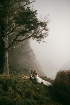 a bride and groom sitting on the side of a mountain