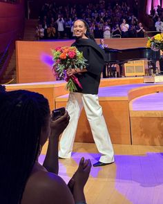 a woman taking a photo with her cell phone while standing in front of an audience