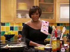 a woman standing in front of a stove with food on top of it and cooking