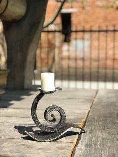 a candle holder on a wooden table with a tree in the background