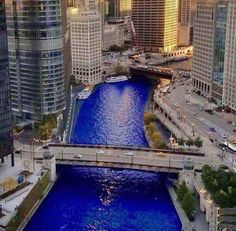 a river running through a city with lots of tall buildings on both sides and a bridge crossing over it