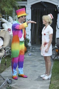 two people dressed up as clowns and one is pointing at something on the ground