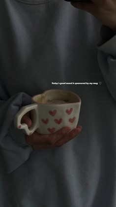 a person holding a coffee cup with hearts on it in their left hand and the words,