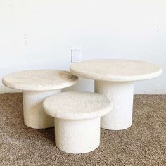 three white stools sitting on top of a carpeted floor