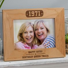 two women are smiling in front of a wooden frame with the words happy 50th on it