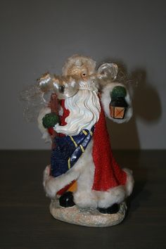 a santa clause figurine sitting on top of a wooden table next to a wall