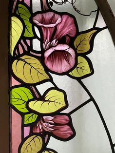 a stained glass window with pink flowers and green leaves on the bottom half of it