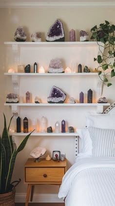 a bedroom with white walls and shelves filled with rocks, candles, and other decorative items