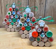 two christmas trees made out of wine corks with buttons and bows on them sitting on a wooden surface