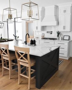 a large kitchen with white cabinets and black island in the center is surrounded by wooden chairs