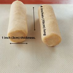 two pieces of bread sitting on top of a white mat next to a measuring ruler