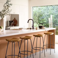 three stools are sitting in front of the kitchen counter with a potted plant on it