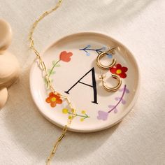 a plate with the letter a on it next to a small figurine and necklace