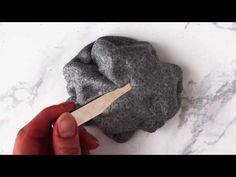 someone using a knife to cut up a rock on a marble counter top with white and gray veining