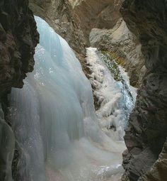 a person standing in front of a waterfall with ice flowing down it's sides