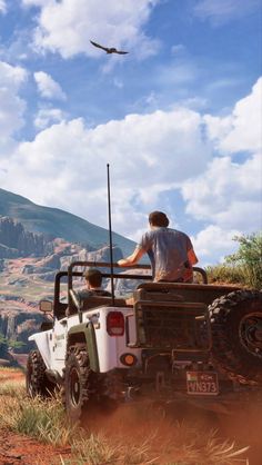 two people are riding in the back of an off - road vehicle with a bird flying overhead