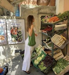 a woman standing in front of a display of fruits and vegetables