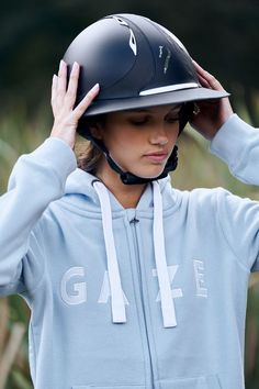 a woman wearing a helmet and holding her hands up to her head