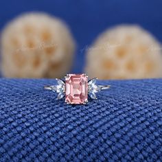 a pink diamond ring sitting on top of a blue cloth