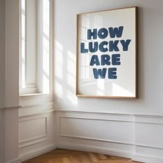 an empty room with a framed poster on the wall and wooden flooring in front of it