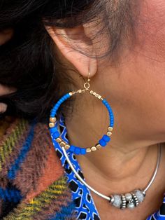 Hoop Earrings with vibrant blue and gold colored beads. Blue Beaded Round Hoop Earrings, Blue Beaded Small Hoop Jewelry, Adjustable Blue Earrings With Large Beads, Blue Hoop Earrings With Ear Wire, Blue Beaded Small Hoop Earrings, Adjustable Small Blue Hoop Earrings, Handmade Blue Beaded Hoop Earrings, Adjustable Small Hoop Earrings In Blue, Blue Earrings With Gold Beads