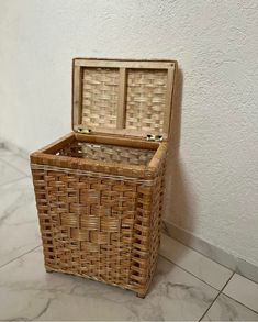 an empty wicker basket sitting on the floor next to a white wall and tile floor