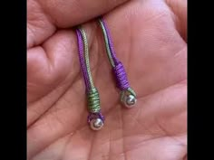 a person holding some kind of purple and green beaded cord with pearls on it