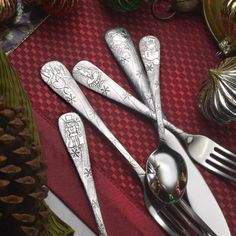 silverware is sitting on top of a red table cloth with christmas decorations in the background