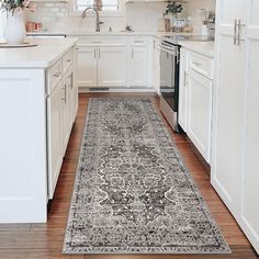 a kitchen with white cabinets and an area rug on the floor in front of the stove