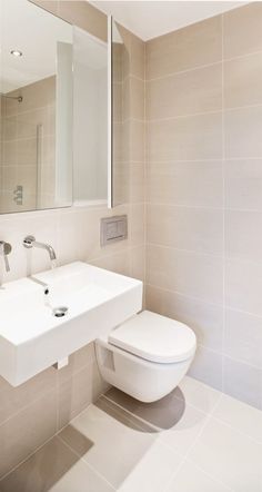 a white toilet sitting next to a sink in a bathroom under a large mirror on the wall