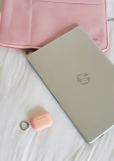 an open laptop computer sitting on top of a bed next to a pink purse and keychain