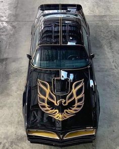 an old black car with gold wings painted on it