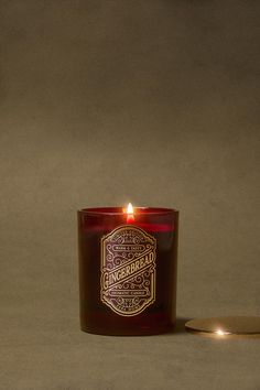 a red candle sitting on top of a table next to a small round object with a lit candle in front of it