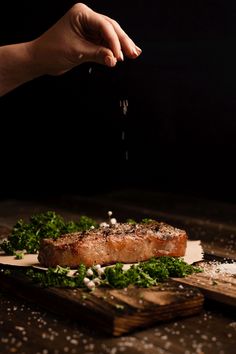 a person is sprinkling seasoning on some meat with parmesan cheese