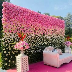 pink and white flowers are covering the backdrop for an outdoor wedding ceremony in front of a large flower - covered wall