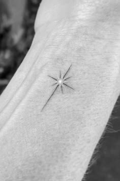 a small star tattoo on the back of a woman's left arm is shown in black and white