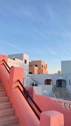 stairs leading up to the top of a building with pink walls and white buildings in the background