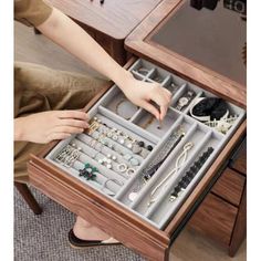 a woman is holding an open drawer with jewelry in it