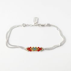 a silver bracelet with red, yellow and blue beaded beads on a white background