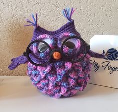 a crocheted owl with glasses sitting on top of a table