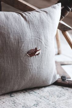 a pillow with a butterfly embroidered on it sitting next to a wooden chair and hammer