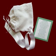 a white bonnet and ribbon on a red background with a note attached to the hat