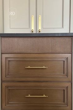 a brown dresser with black top and gold handles